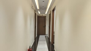 A hallway with a fire extinguisher, recessed lighting, and a door at the end. - Hotel Raddione (Gandhinagar)