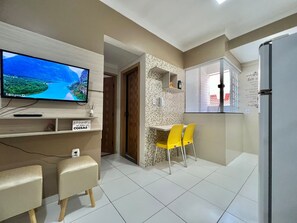 Eine moderne Küche mit Flachbildfernseher, Kühlschrank und Essbereich mit gelben Stühlen.