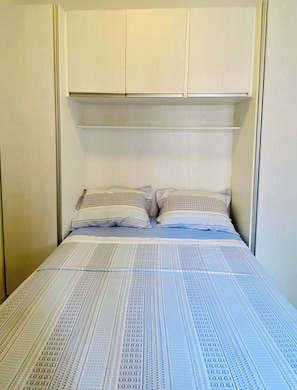 Ein Schlafzimmer mit einem Bett, zwei Kissen und einem Kopfteil mit Stauraum.