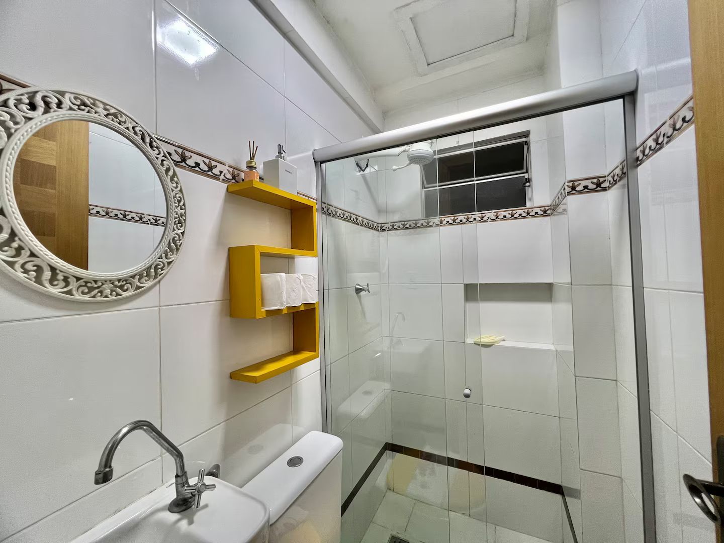A bathroom with a white sink, mirror, and shower enclosure.