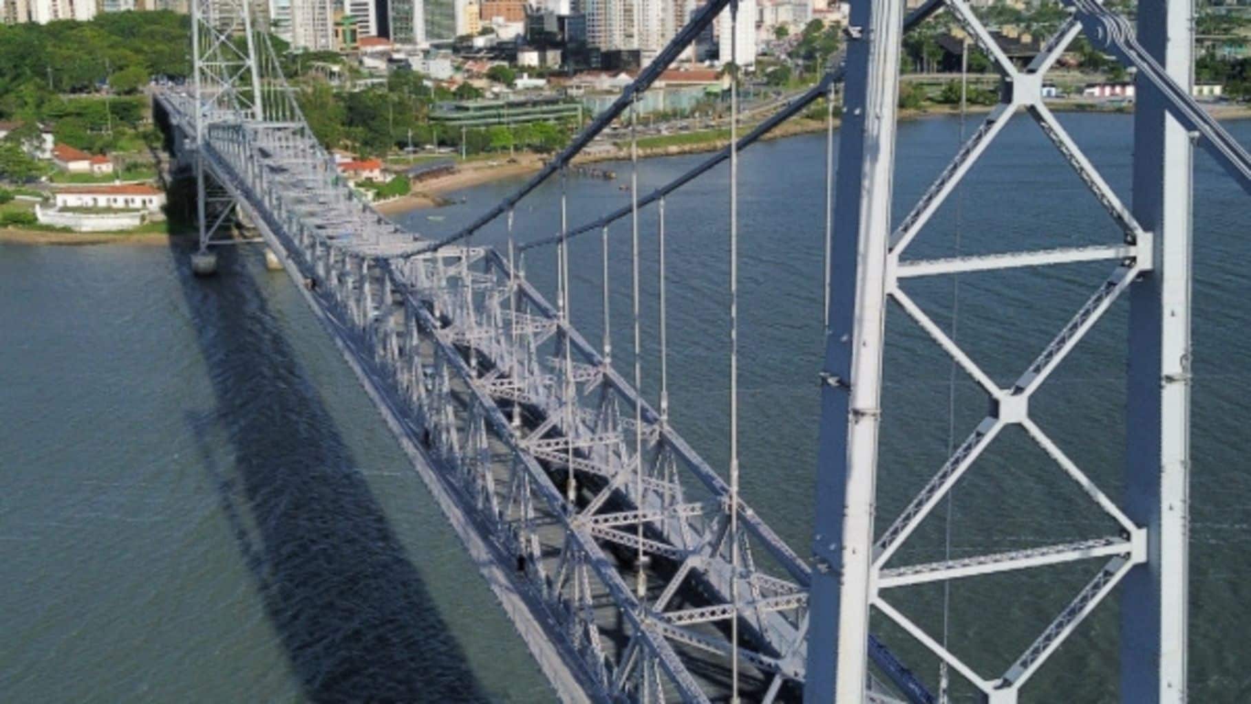 Een grote hangbrug met een ingewikkeld staalwerkconstructie over een wateroppervlak.