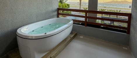 A spa area with a hot tub, wooden deck, and a view of the sea.