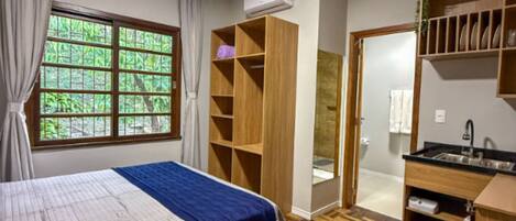 A bedroom with a bed, a wardrobe, a bathroom, and a kitchenette.