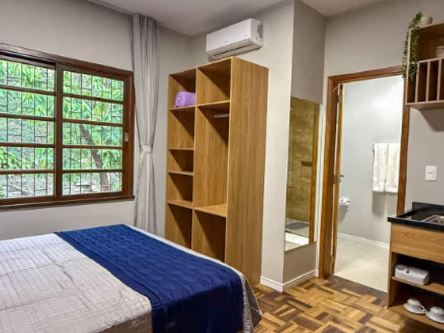 A bedroom with a bed, a wardrobe, a bathroom, and a kitchenette.