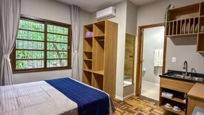 A bedroom with a bed, a wardrobe, a bathroom, and a kitchenette. - Casa Ponte Floripa (Florianópolis)