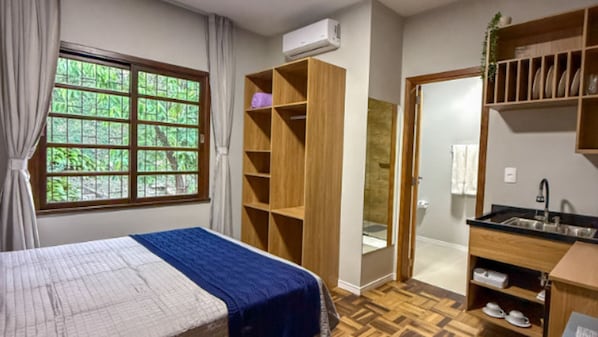 Un dormitorio con cama, armario, baño y kitchenette.