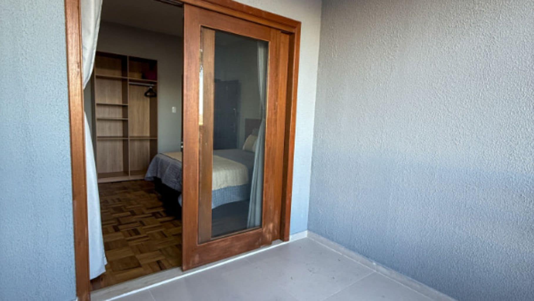 A room with a wooden door, a bed, and a wardrobe.