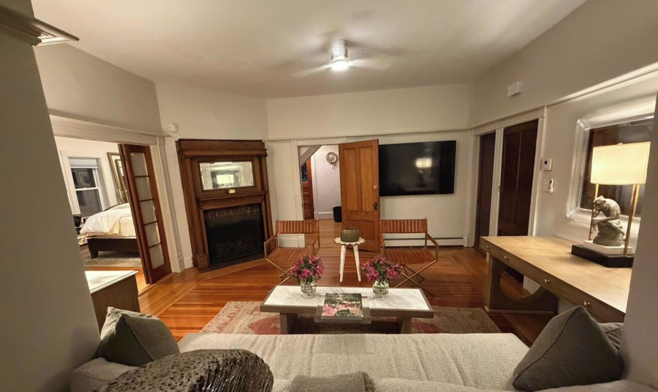 A living room with a fireplace, a television, and a dining area with chairs.
