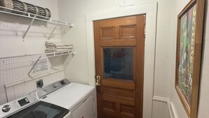 Lavandería con lavadora, tendedero y una puerta que da a otra habitación.