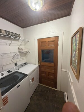 A laundry room with a washing machine, drying rack, and a door leading to another room. - Stunning downtown Mystic 4 bedroom 2 kitchen newly renovated historic home (Mystic)