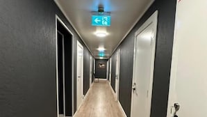 A hallway with doors on both sides, a light fixture on the ceiling, and a directional sign.