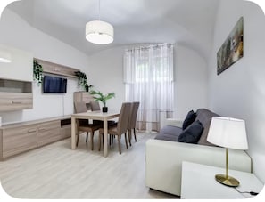 Un espace de vie moderne comprenant un coin repas, un canapé et un téléviseur fixé au mur.