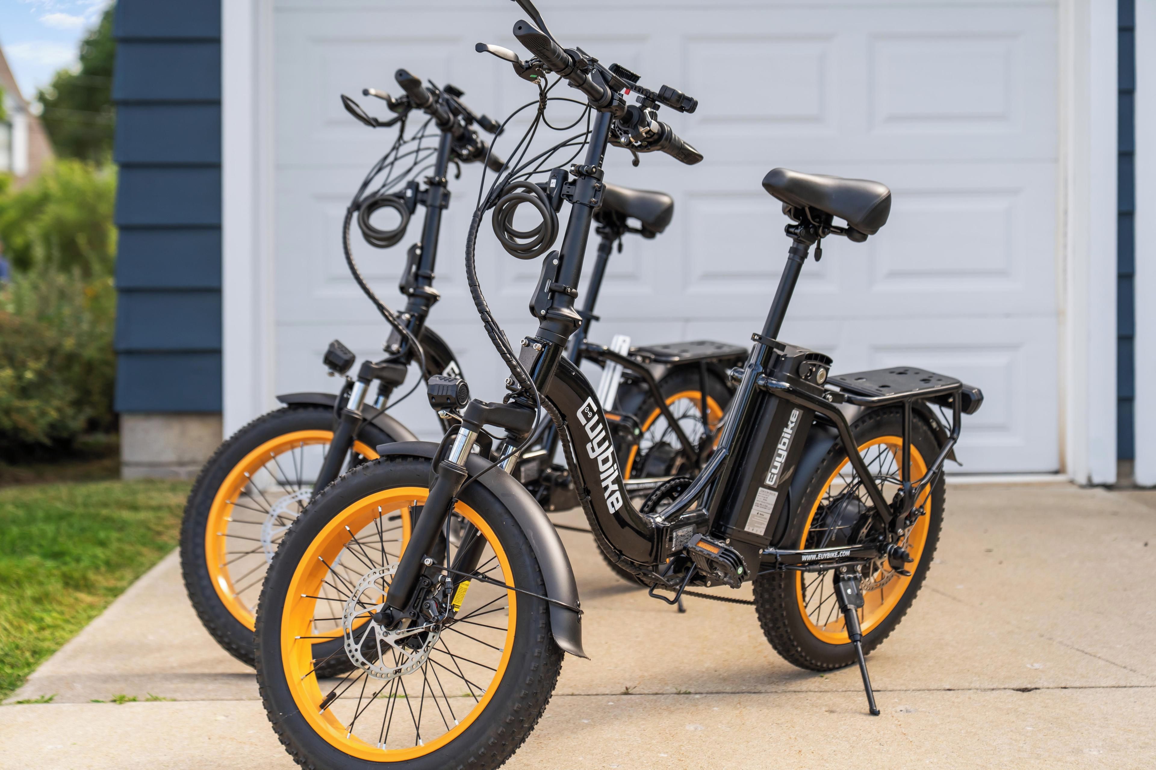 Dos bicicletas eléctricas estacionadas en un camino de entrada frente a un garaje.