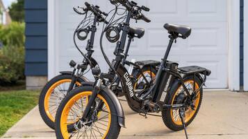 Dos bicicletas eléctricas estacionadas en un camino de entrada frente a un garaje.
