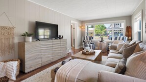 A modern living room with a flat-screen TV, a large sofa set, and a dining area with a round table.