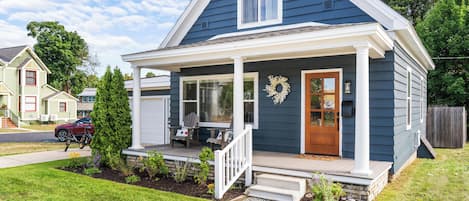 A two-story house with a front porch, a garage, and a well-maintained lawn.