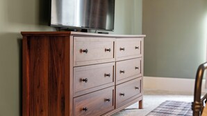 A wooden dresser with drawers and a television on top.