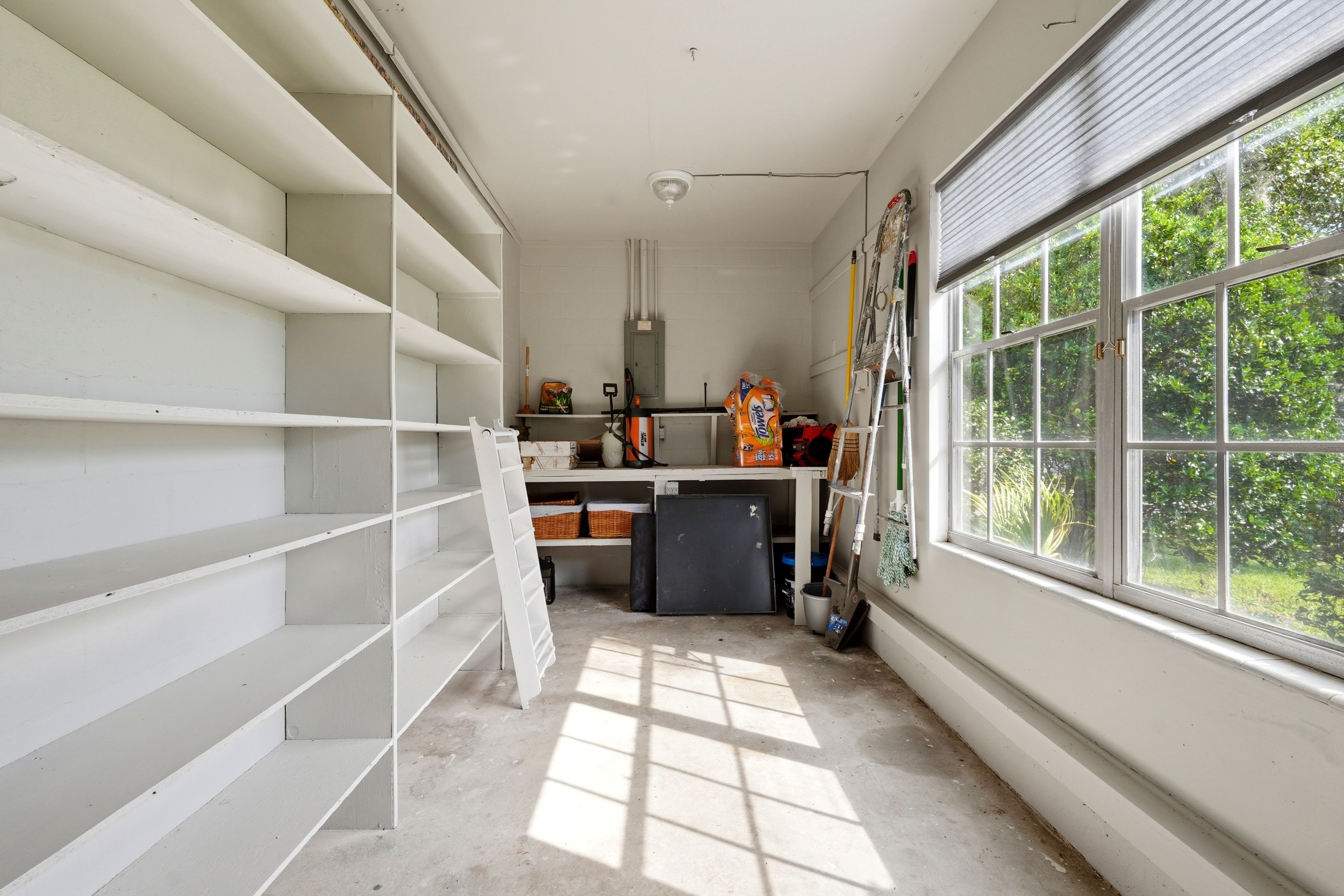 A room with white walls, a large window, and a ceiling fan.