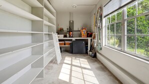Ein Zimmer mit weißen Wänden, einem großen Fenster und einem Deckenventilator.