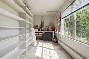 Una habitación con paredes blancas, un ventanal grande y un ventilador de techo.