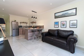 A modern kitchen with a central island, bar stools, and a refrigerator. - Comfortable Living within walking distance to go swim, surf, dine or just relax (Cape Town)