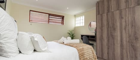 A bedroom with a bed, a desk, and a wardrobe.
