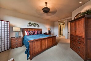 Un dormitorio con una cama de madera grande, una mesita de noche, un aparador y una lámpara de techo.