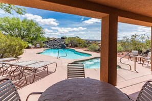 A pool area with lounge chairs, a table, and a view of a rocky landscape. - Private Red Rock Haven (Santa Clara)