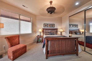 A bedroom with a bed, a chair, two bedside tables with lamps, a ceiling fan, and a large mirror on the wall. - Private Red Rock Haven (Santa Clara)