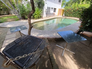 Een achtertuin met een zwembad, een barbecue en tuinmeubilair.