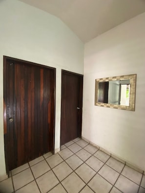 Ein Flur mit zwei Holztüren und einem an der Wand befestigten Spiegel.