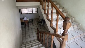 A staircase with wooden balusters leading to a landing with a table and chairs. - Tzalahua House (Manzanillo)