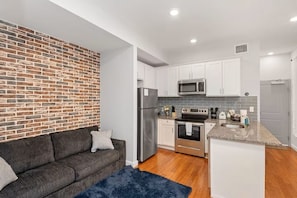 A compact kitchen with white cabinets, a stainless steel refrigerator, a microwave, and an oven. - Central OTR, Lux King Bed, 2 Smart TVs, Sleeps 4ppl, Fast Wifi, 2nd Floor (Cincinnati)