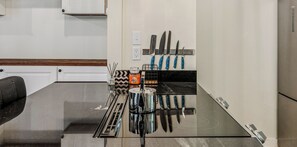 A kitchen with a black countertop, a stove, and a knife rack with various knives. - Cozy Quechee Hollow Condo with Pond Views & Club Access (Hartford)