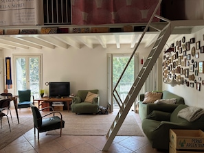 Ein Wohnzimmer mit Treppe, Fernseher und einer mit Bilderrahmen versehenen Wand.