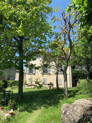 Ein Gebäude mit einem Garten, einer Steinmauer und einem großen Felsen im Vordergrund.
