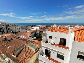 Ein Küstenwohngebiet mit terrakottafarbenen Dächern, weißen Gebäuden und freiem Blick auf das Meer.