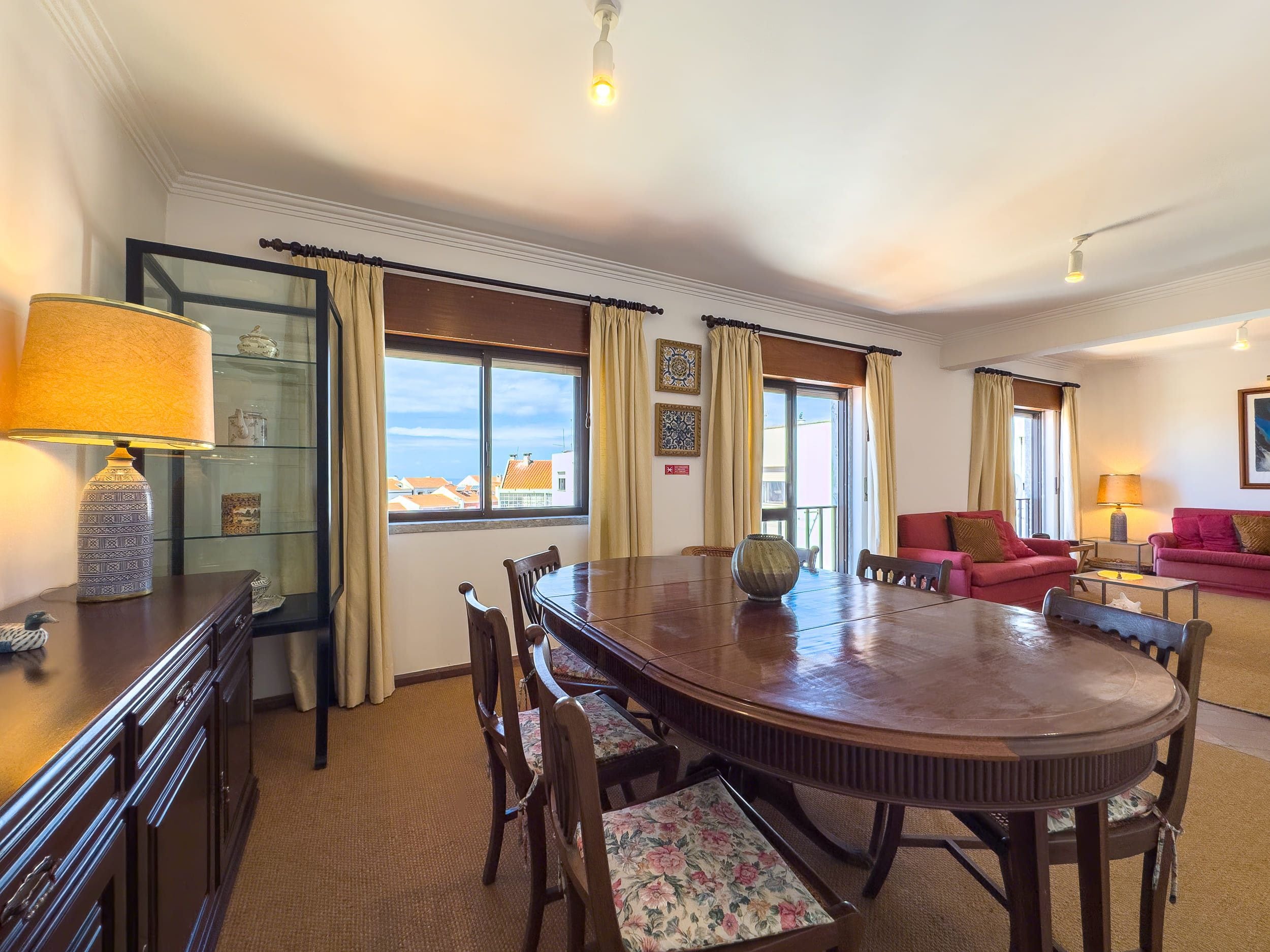 Une chambre d’hôtel équipée d’une table à manger, de chaises, d’un canapé, d’une lampe et offrant une vue sur la ville par la fenêtre.