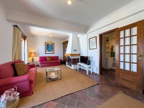 Ein Wohnzimmer mit einem roten Sofa, einem Fernseher und einem Kamin.