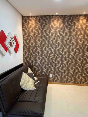 A modern room with a patterned wall, a dark brown leather sofa with cushions, and a white floor. - Apartment 201 · Practical flat close to everything (Belém)