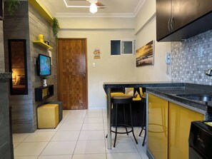 Eine moderne Küche mit integriertem Fernseher, einer Holztür und einer Bar mit Hockern.
