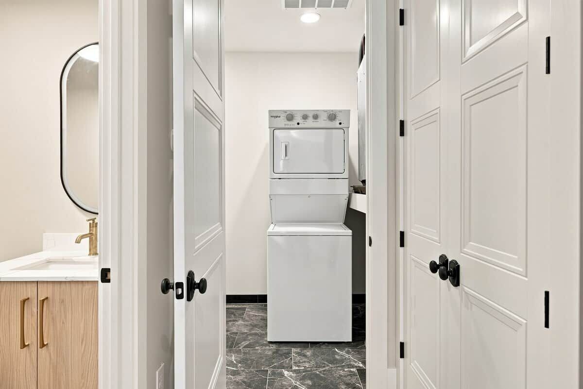 Un baño de hotel con un lavamanos blanco, un espejo y una lavadora blanca.