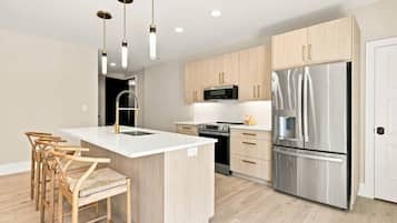Una cocina moderna con una isla central, electrodomésticos de acero inoxidable y armarios de madera.