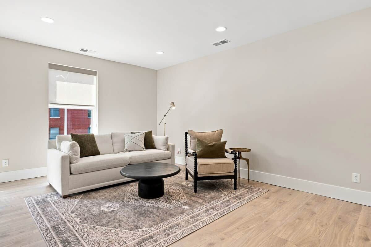Un salon avec un canapé, un fauteuil, une table basse et un tapis.
