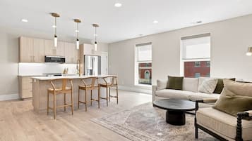 A modern kitchen with a central island, bar stools, and pendant lighting.