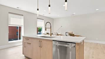 Una cocina moderna con lavavajillas de acero inoxidable, armarios de madera e iluminación colgante.