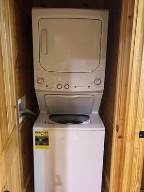 A compact, white front-loading washer and dryer unit with a control panel, ENERGYGUIDE sticker, and a wooden enclosure. - Cozy Bear 2 located on Turkey Nest Road (Gatlinburg)
