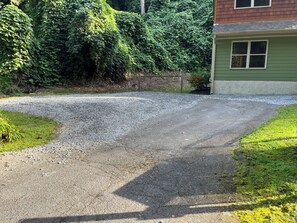 Ein gepflegter Schotterweg führt zu einem Haus mit grüner Fassade und einem Fenster.