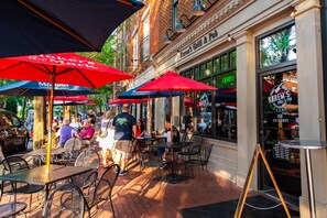 Un espace extérieur aménagé avec des tables et des chaises, des parasols et une façade en briques.