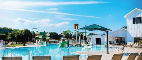 A swimming pool with lounge chairs and a water slide.